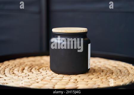 Stilvolles schwarzes Glas mit einem Holzdeckel für eine Kerze oder Creme Stockfoto