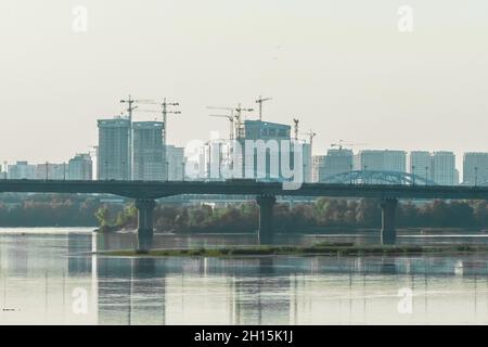 Eine große Brücke zur Stadt über den Fluss vor dem Hintergrund des Stadtbildes und der urbanen Landschaftsarchitektur. Stockfoto