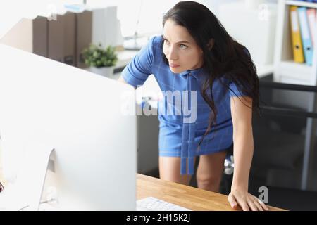 Überraschte verärgerte Frau, die am Arbeitsplatz einen Computermonitor ansah Stockfoto