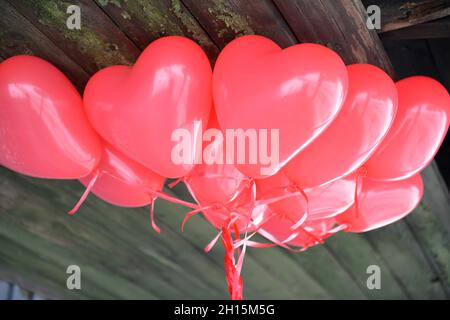 Rote Herz Ballons-Love Story Valentinstag auf Holz Hintergrund. Farbige Ballons für Hintergrund Stockfoto