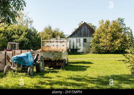 Alte Scheune, Traktor und Landmaschinen im grünen Feld Stockfoto