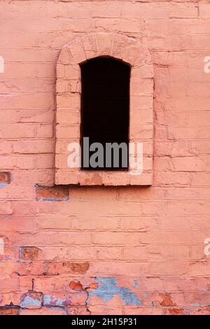 Foto von alten und rissigen roten Ziegelwänden mit gewölbtem Fenster. Stockfoto