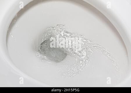 Bewegungsunschärfe des Spülwassers in der Toilettenschüssel. Sanitär, Hausreparatur und Wasserschutz Konzept. Stockfoto