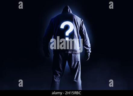 Foto von gruseligen Horror fremden Stalker Mann in schwarzer Kapuze und Kleidung auf dunklem Hintergrund mit leuchtenden Frage-Symbol auf dem Rücken. Stockfoto