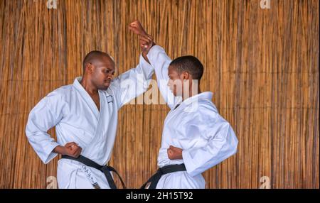 Afrikanische Männer, die Kumit an einem Dojo auf einem blauen Boden aufführen Stockfoto