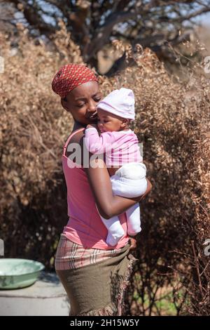 Alleinerziehende junge afrikanische Mutter in einem Dorf in Botswana, das Drama alleinerziehender Mütter aus der dritten Welt Stockfoto