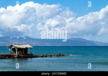 Kreta, Griechenland Agia Marina Strand in der Nähe von Chania kleiner Felsbrecher mit Klippen und Bergen am Horizont Stockfoto