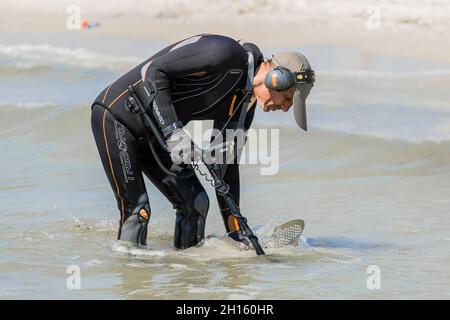 Ukraine, Iron Port - 01. September 2020: Ein Mann mit einem speziellen Gerät und Ausrüstung Metalldetektor auf der Suche nach verlorenen Schmuck und Gold im Meerwasser in der Nähe Stockfoto