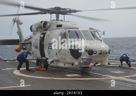 211011-N-EF547-1102 BAY OF BENGAL (OKT 11, 2021) Seeleute an Bord des Lenkraketen-Kreuzers USS Lake Champlain (CG 57) der Ticonderoga-Klasse sichern sich während DES MALABAR 2021, 11. Oktober 2021, einen SH-60J Sea Hawk Hubschrauber der Japan Maritime Self-Defense Force (JMSDF) zum Flugdeck. MALABAR 2021 ist eine maritime Übung, die darauf ausgerichtet ist, die Integration zu verbessern, gemeinsame Prioritäten und Anliegen im Bereich der Sicherheit im Seeverkehr anzugehen, die Interoperabilität und Kommunikation zu verbessern und dauerhafte Beziehungen zwischen der Royal Australian Navy, der indischen Marine, den japanischen maritimen Selbstverteidigungskräften und den US-Seekräften zu stärken. (USA Nav Stockfoto