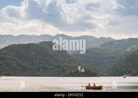 BLED, SLOWENIEN - 12. JUNI 2021: Touristen auf einem Ruderboot vor Blejsko ostrvo, blutete Insel, auf dem Bleder See oder Blejsko Jezero, mit der Annahme von Stockfoto