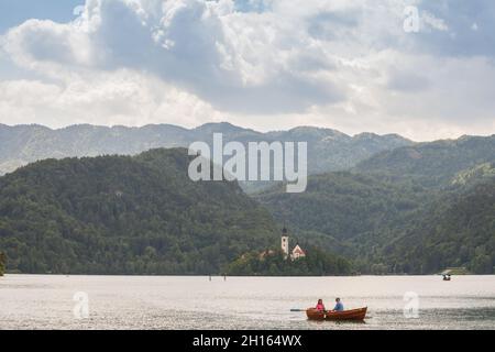 BLED, SLOWENIEN - 12. JUNI 2021: Touristen auf einem Ruderboot vor Blejsko ostrvo, blutete Insel, auf dem Bleder See oder Blejsko Jezero, mit der Annahme von Stockfoto