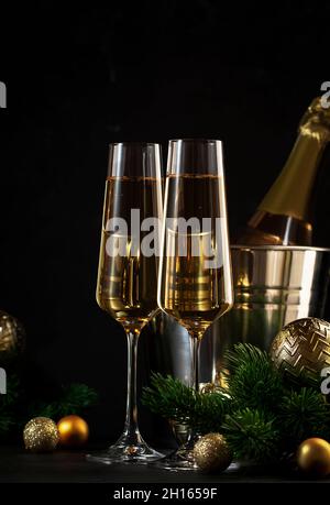 Zwei Sektgläser und goldene weihnachtsdekoration auf schwarzem Hintergrund. Happy New Year oder Merry Christmas Komposition Stockfoto
