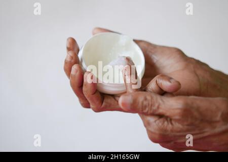 Ältere Frau, die Petroleum-Gelee verwendet, isoliert auf Weiß Stockfoto