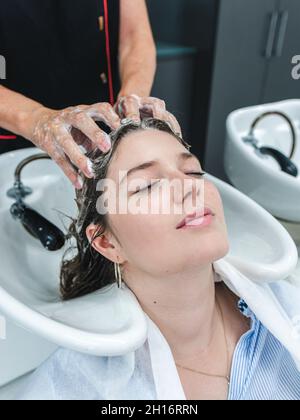 Konzentrierte weibliche Blumendesignerin in Schürze, die am Tisch steht und mit blühenden Rosen in der Werkstatt eine Blumenkomposition kreiert Stockfoto