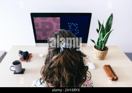 Von oben auf weibliche Designerin, die modernen Computer verwendet, während sie im modernen Büro arbeitet Stockfoto