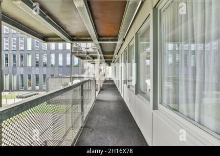 Enge Halle mit Tür und Fenstern gegen rostige Metallzäune unter Dach mit Balken am Tag Stockfoto