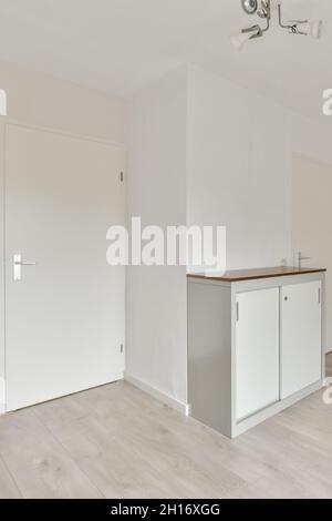 Moderne Innenausstattung mit Tisch und Kronleuchter über dem Boden im hellen Haus mit weißen Türen Stockfoto