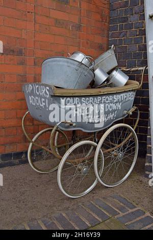 Ein Requisiten-Kinderwagen im Stil des 2. Weltkriegs voller Kochtöpfe für das Recycling in Flugzeuge bei der Great Central Railway, Loughborough, Leicestershire Stockfoto