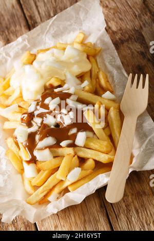 Patatje Oorlog Dutch war Fries gekrönt mit Mayonnaise, einer dicken Erdnusssauce im indonesischen Stil, und rohen Zwiebeln in der Nähe auf dem Teller auf dem Tisch. Vertica Stockfoto