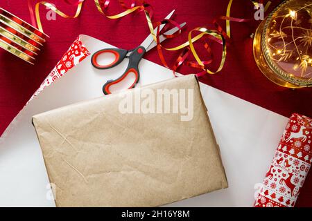 Familie bereitet sich auf Weihnachten vor. Draufsicht auf die Geschenkverpackung von Händen. Schachteln mit Geschenken, buntem Geschenkpapier, Scheren und Bändern. Stockfoto