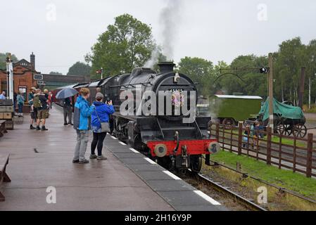Eisenbahnliebhaber beobachten die ehemalige Dampflokomotive LMS 8F 48305 bei der Ankunft in Quorn & Woodhouse Statio bei der Great Central Heritage Railway, Leicestershire Stockfoto