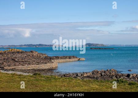 Blick auf Herm und Jethou über einen Wellenbrecher von Belle Greve Bay, Guernsey Stockfoto