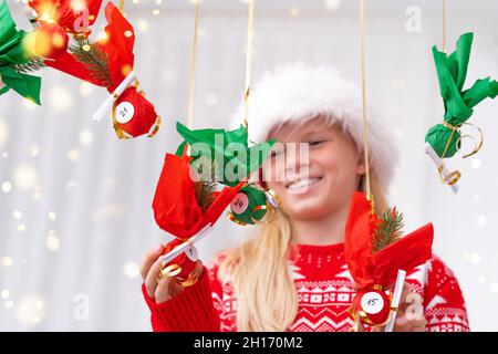 Kind Mädchen Eröffnung kleine Geschenke Überraschungen Adventskalender an der Wand hängen. Frohe Weihnachten und Neujahr. Stockfoto