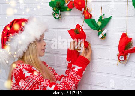 Kind Mädchen Eröffnung kleine Geschenke Überraschungen Adventskalender an der Wand hängen. Frohe Weihnachten und Neujahr. Stockfoto