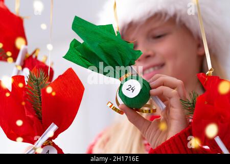 Kind Mädchen Eröffnung kleine Geschenke Überraschungen Adventskalender an der Wand hängen. Frohe Weihnachten und Neujahr. Stockfoto