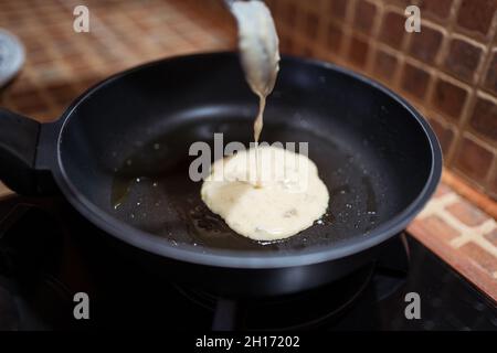 Crop anonyme weibliche Kochen leckere Pfannkuchen in der Pfanne auf Herd in der Küche Stockfoto