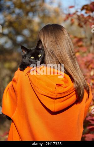 Schwarze Katze ruht auf der Schulter einer jungen Frau Stockfoto