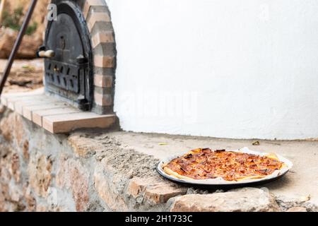 Pizza aus einem weiß lackierten, handgefertigten Holzofen, der auf der Außenseite gebaut wurde Stockfoto