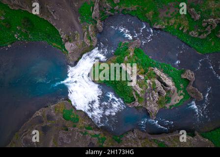 Drohnenansicht des schnellen Flusses, der zwischen rauhen steilen felsigen Küsten fließt, die mit grünem Moos bedeckt sind, in der wilden Natur Islands Stockfoto