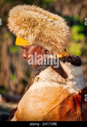 Zwei ältere Frauen aus dem südlichen Afrika, die in einer traditionellen Tracht mit Hut und Kuh gekleidet sind, verstecken sich in einem Dorf auf dem Land Stockfoto