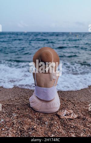 Talentierte afroamerikanische Musikerin, die im Sommer bei Sonnenuntergang am Sandstrand Cello spielt Stockfoto