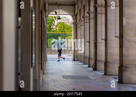 Pariser Arkade mit einer Löwenskulptur im Hintergrund, aufgenommen an einem Frühlingsmorgen mit einem vorbeiziehenden Jogger Stockfoto