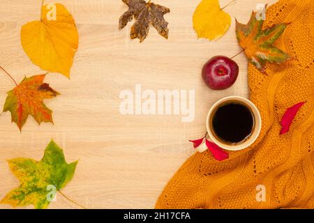 Herbstliche Komposition mit einer Tasse Kaffee, Marschmalchen, Pullover und Blättern. Von oben auf einem hölzernen Hintergrund aufgenommen. Stockfoto