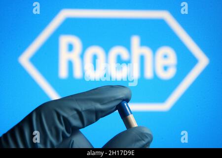 Ukraine. Oktober 2021. In dieser Abbildung ist eine Medikamentenpille in Form einer Kapsel in einer Hand zu sehen, die in einem medizinischen Handschuh gekleidet ist und im Hintergrund das Logo der Roche Holding AG eines Pharmaunternehmens trägt. Kredit: SOPA Images Limited/Alamy Live Nachrichten Stockfoto