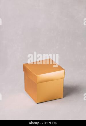 Goldene Geschenkbox auf grauem Hintergrund. Speicherplatz kopieren. Festliche Feiertage im Hintergrund. Stockfoto