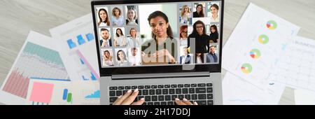 Frau, die auf dem Boden in der Nähe von Dokumenten sitzt und per Videoverbindung mit dem Mitarbeiterteam aus der Draufsicht kommuniziert Stockfoto