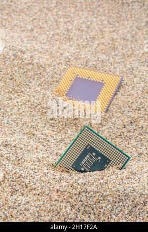 Uralte Computer-CPUs, die in einem Sandhaufen für Computer-Friedhof, Legacy-Computing begraben sind. Intel Mobile Computing Merom und AMD Duron cpu präsentieren. Stockfoto