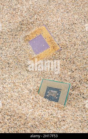 Uralte Computer-CPUs, die in einem Sandhaufen für Computer-Friedhof, Legacy-Computing begraben sind. Intel Mobile Computing Merom und AMD Duron cpu präsentieren. Stockfoto