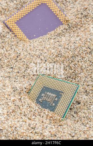 Uralte Computer-CPUs, die in einem Sandhaufen für Computer-Friedhof, Legacy-Computing begraben sind. Intel Mobile Computing Merom und AMD K6 cpus vorhanden. Stockfoto