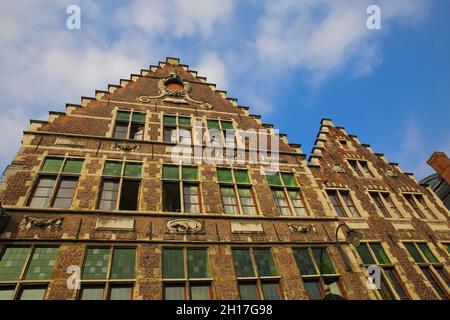 Niedriger Winkel Blick auf mittelalterliche Backsteinhaus-Fassade mit typisch belgischem Stufendach gegen blauen Himmel mit Wolken - Gent, Belgien Stockfoto