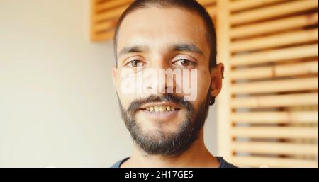 Ein indischer junger Mann, der drinnen steht und die Kamera anschaut Stockfoto