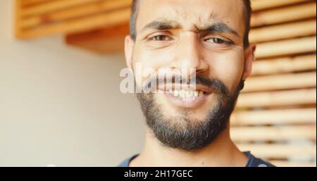 Ein indischer junger Mann, der drinnen steht und die Kamera anschaut Stockfoto