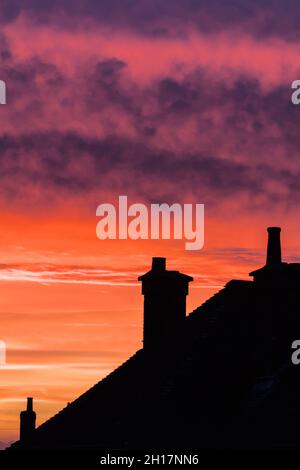 Silhouette von Roof Tops und Kaminen gegen Einen Pink and Purple Sunset, Großbritannien Stockfoto