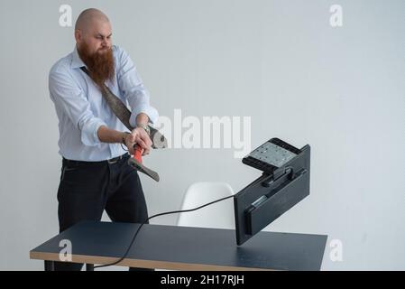 Gestresste verrückte Geschäftsmann zerschlagen seinen Computer im Büro mit Axt Problem Konzept. Der Mann hat Probleme bei der Arbeit und Frustration. Stockfoto