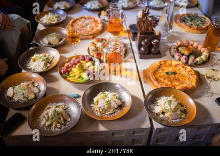 Food-Konzept, Tisch mit verschiedenen Snacks darauf gelegt. Salat mit Lachs, caesar skuric, eingelegten Pilzen, Brot Stockfoto