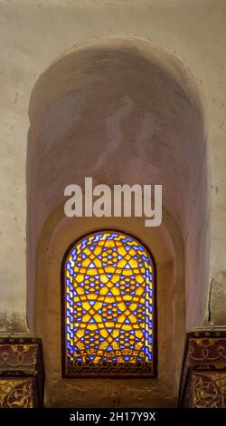 Eingelassenes perforiertes Stuckfenster, das mit buntem Fleckglas mit geometrischen kreisförmigen Mustern und Blumenmustern verziert ist, im historischen Qalawun-Komplex aus der Mamluk-Ära, in der Moez Street, Kairo, Ägypten Stockfoto